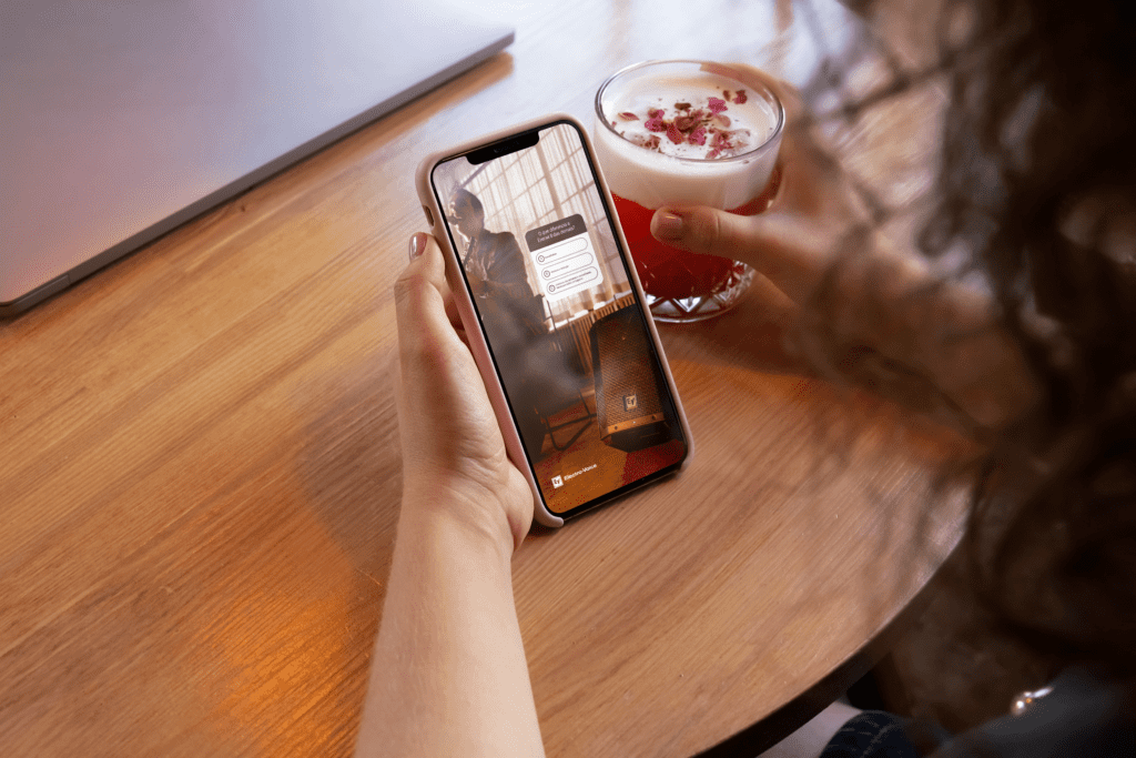 Pessoa segurando um copo e o smartphone na outra mão.